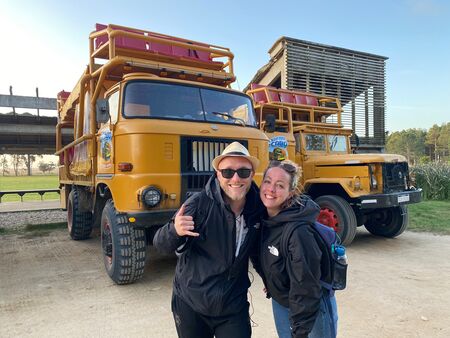 Zwei Reiesende Anfang 30jährige vor zwei gelben Allrad Trucks. Sie sehen glücklich aus. Cabo Poloio, Uruguay.