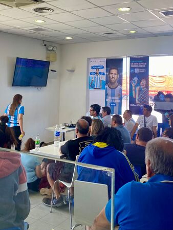Viele Argentinier sitzen versammelt in einer Tankstelle irgendwo in Patagonien und schauen das WM Fußball-Finale 2022.