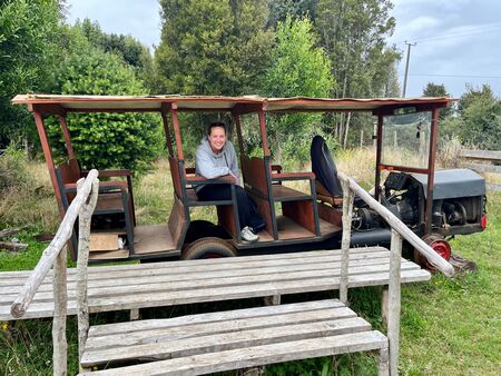 Eine lächelnde junge Frau sitzt in einem Selbstgebauten Zug und freut sich auf das Abenteuer. Der „Zug“ besteht aus dem Lockführer-Bereich und 3 Doppelsitzbänken. Er ist hauptsächlich aus Holz und steht am ebenfalls selbstgebauten kleinen Bahnhofseinstieg