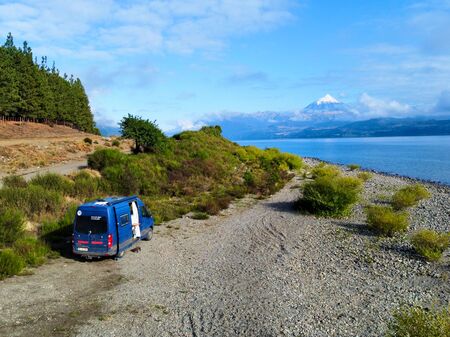 Wow! Ein blauer Van steht direkt am Ufer eines strahlend blauen Sees. Im Hintergrund deutlich zu sehen ist der Lanín Vulkan in Argentinien. Die Sonne scheint und es sieht nach einem absoluten Paradies für Overlander aus.