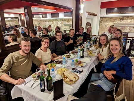 Eine Gruppe von Freunden sitzt an einem langen Tisch in einem Restaurant in Salta, Argentinien, und genießt ein gemeinsames Abendessen mit Wein und verschiedenen Gerichten