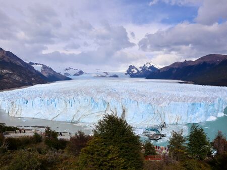 Der berühmte Perito Moreno Gletscher in seiner vollen Pracht bei bewölktem Himmel in der MItte der Anden liegend.