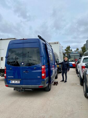 Ein blauer Van im Hafen von Montevideo stehend ist von hinten zu sehen. Rechts neben ihm ein junger Mann, der sich riesig freut, ihn endlich in Empfang nehmen zu können.